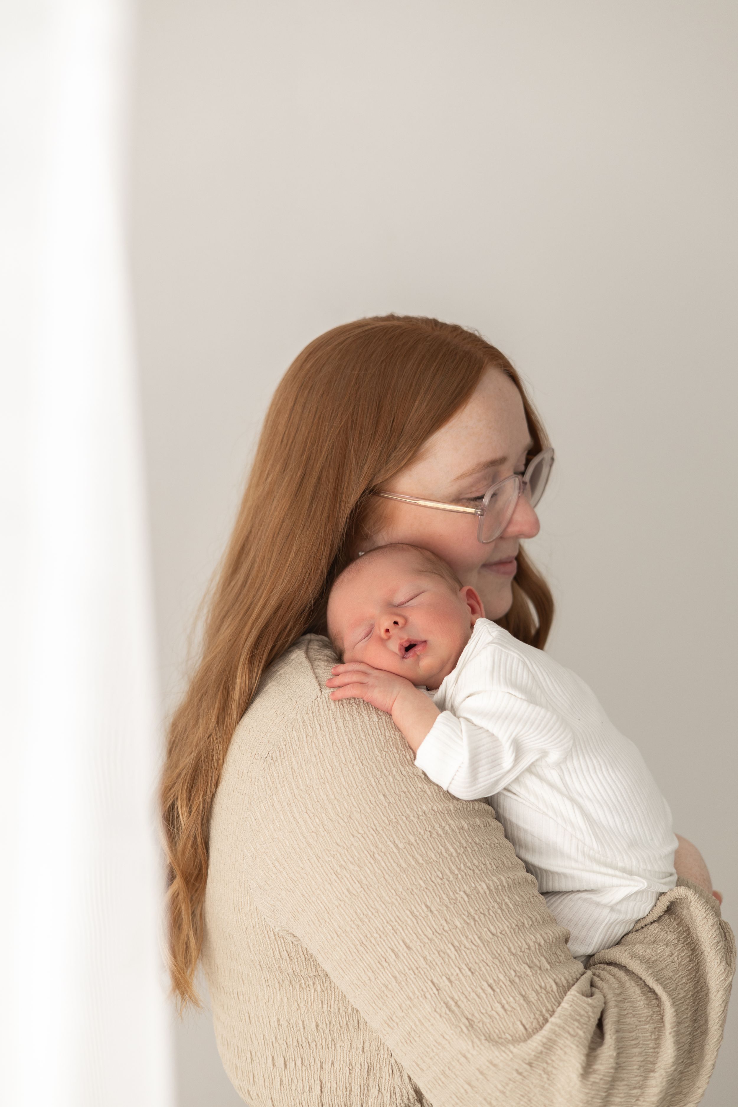 Mum tenderly holds her sleeping newborn baby baby photographer Nottingham newborn session