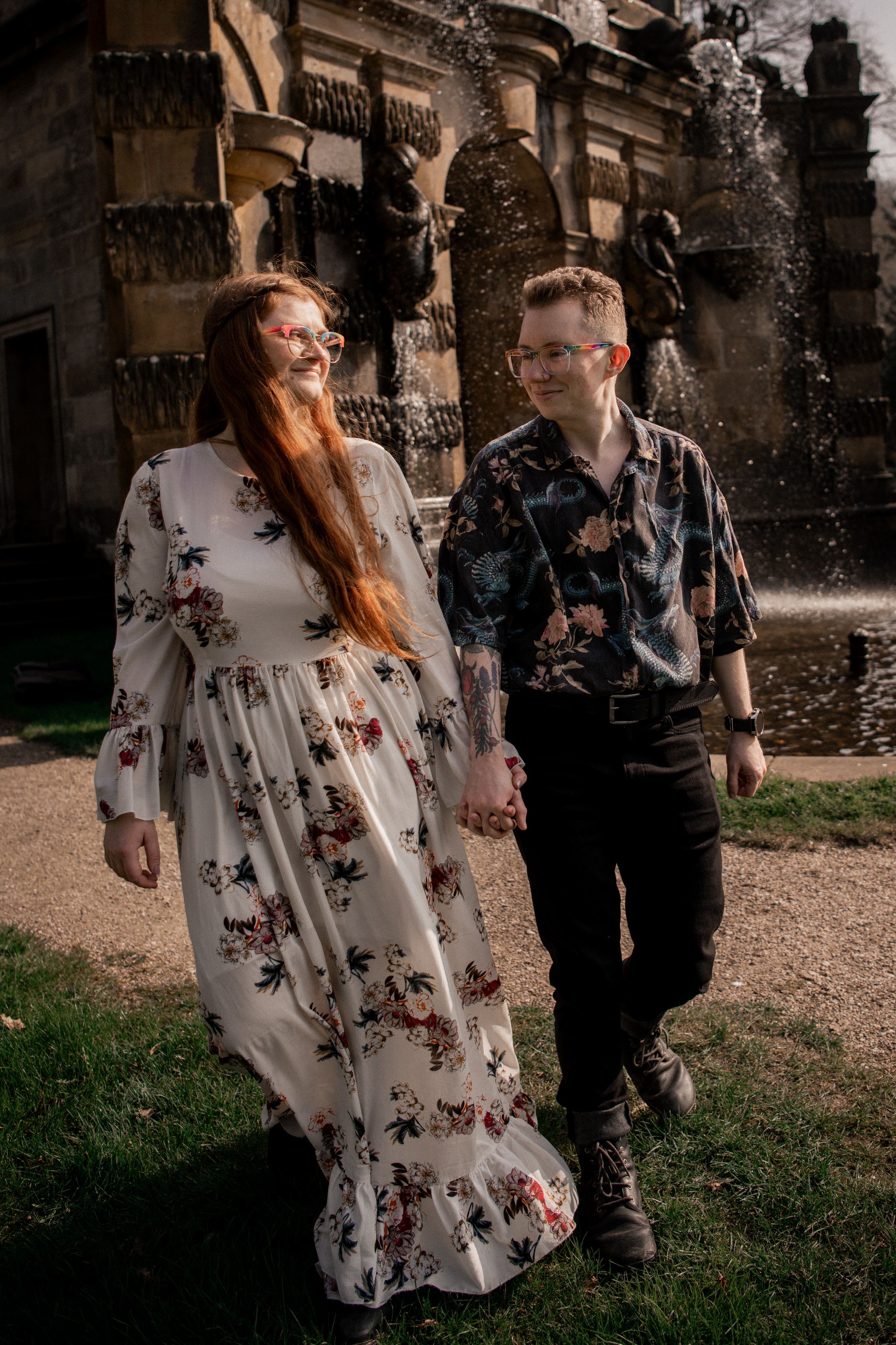 A couple in coordinating floral outfits poses together near ornate architecture.