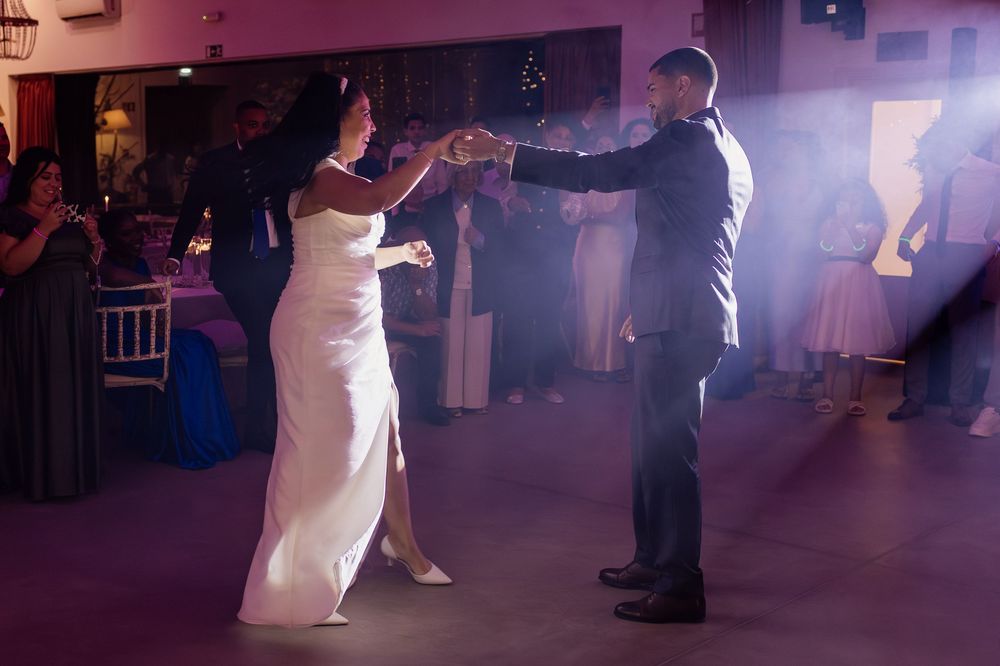 Wedding guests dancing together on a dimly lit dance floor with purple lighting during an evening reception celebration.