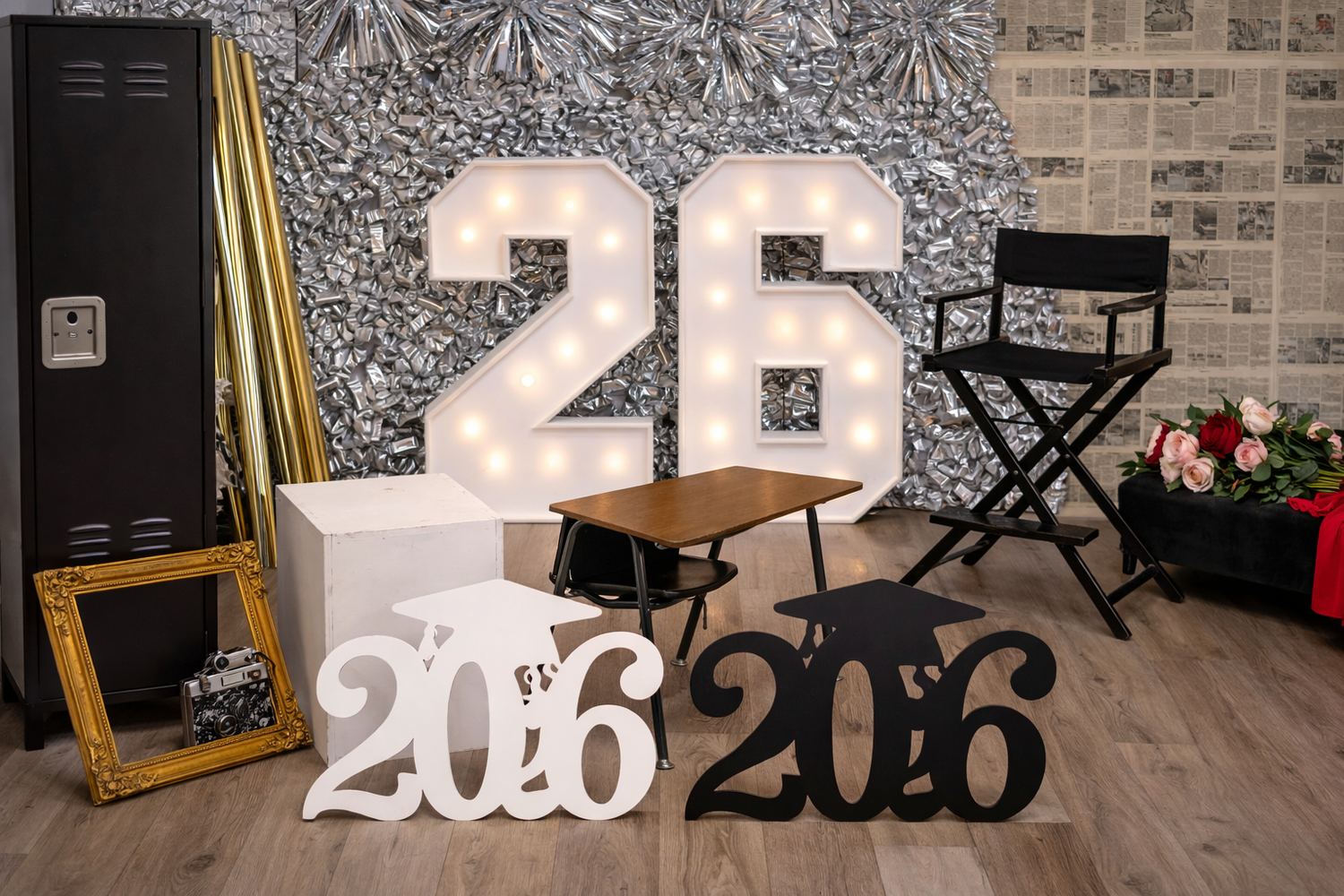 Graduation photo backdrop with illuminated number 26 marquee letters and decorative 2026 signs.