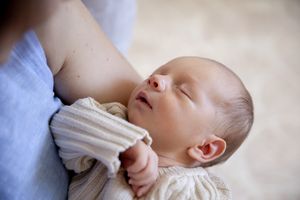 Mother holding new born in lounge room at new born professional photo shoot