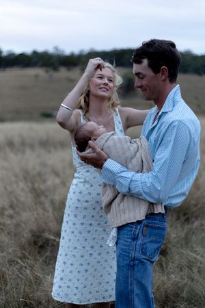 Mother fixing father's hair while he's holding new born during a professional newborn photo shoot.