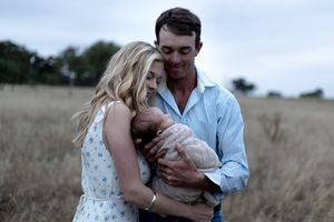 Father kissing mother while holding their newborn baby during a professional newborn photo shoot.