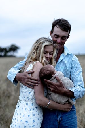 father hugging mother and new born  in professional new born photo session