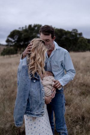 Father kissing mother who is feeding new born in professional new born photo session
