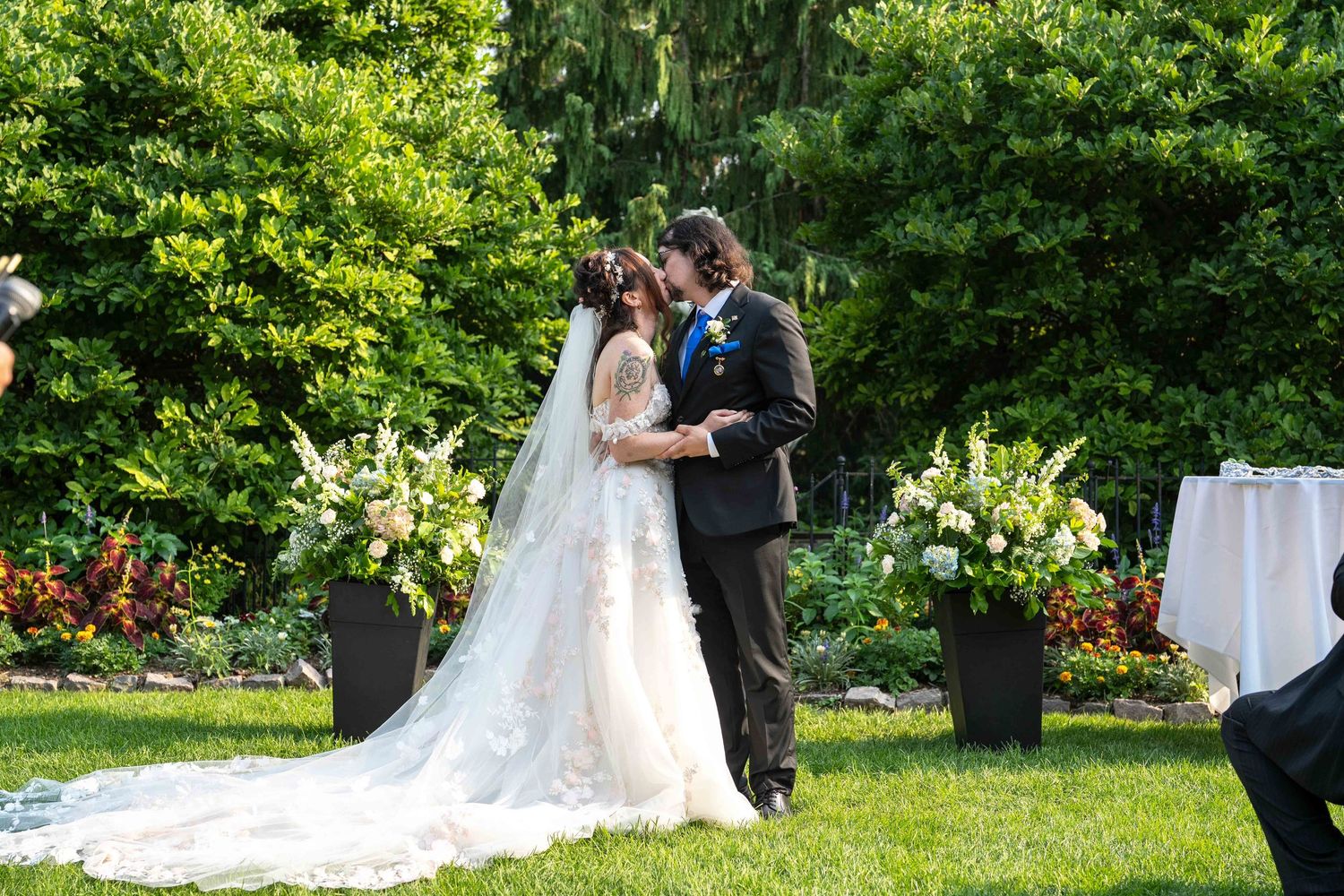 Bride and groom share first kiss at outdoor garden wedding ceremony at Toledo Zoo Wedding Venue
