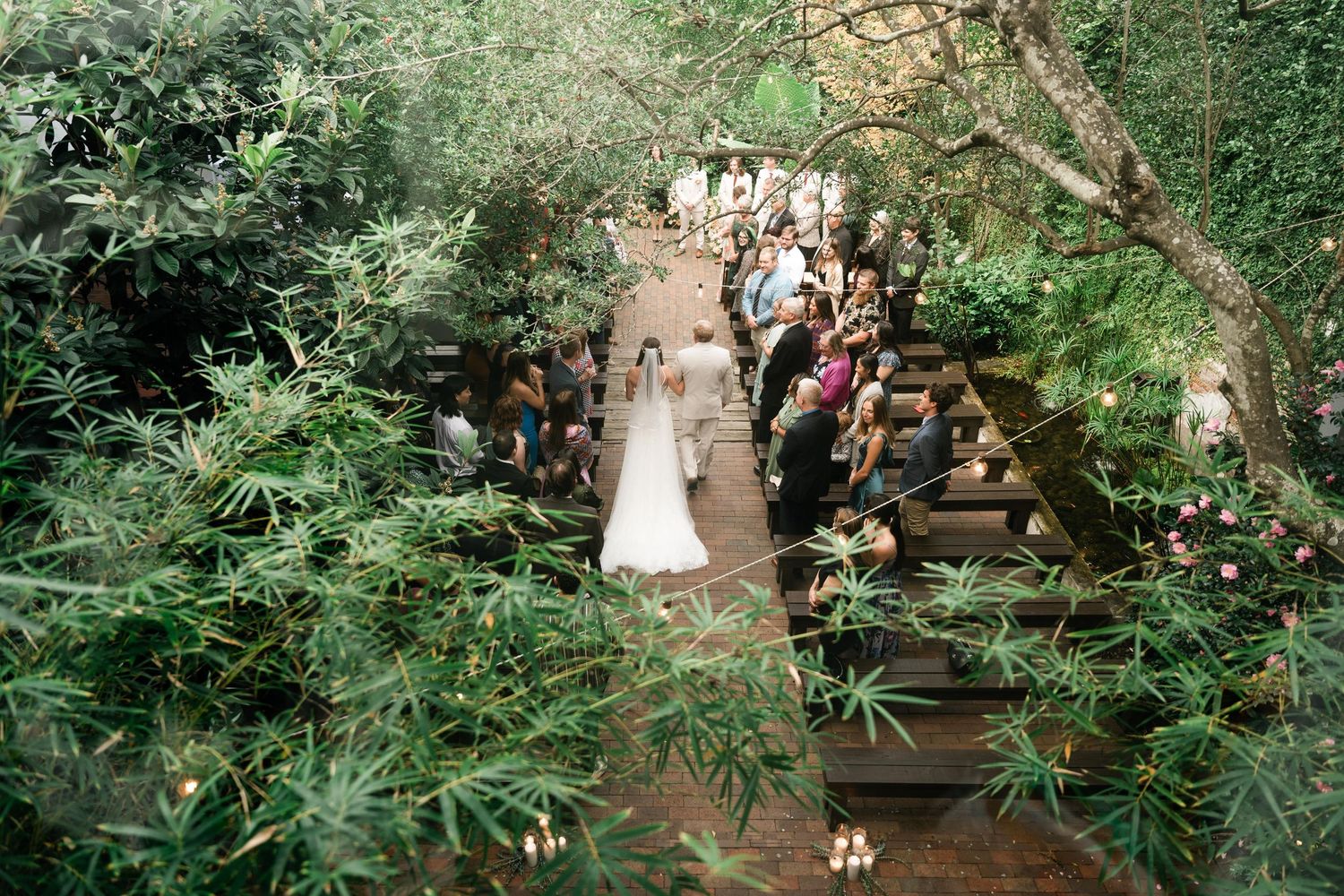 A romantic garden wedding ceremony features lush greenery and floral arrangements in a serene outdoor setting.