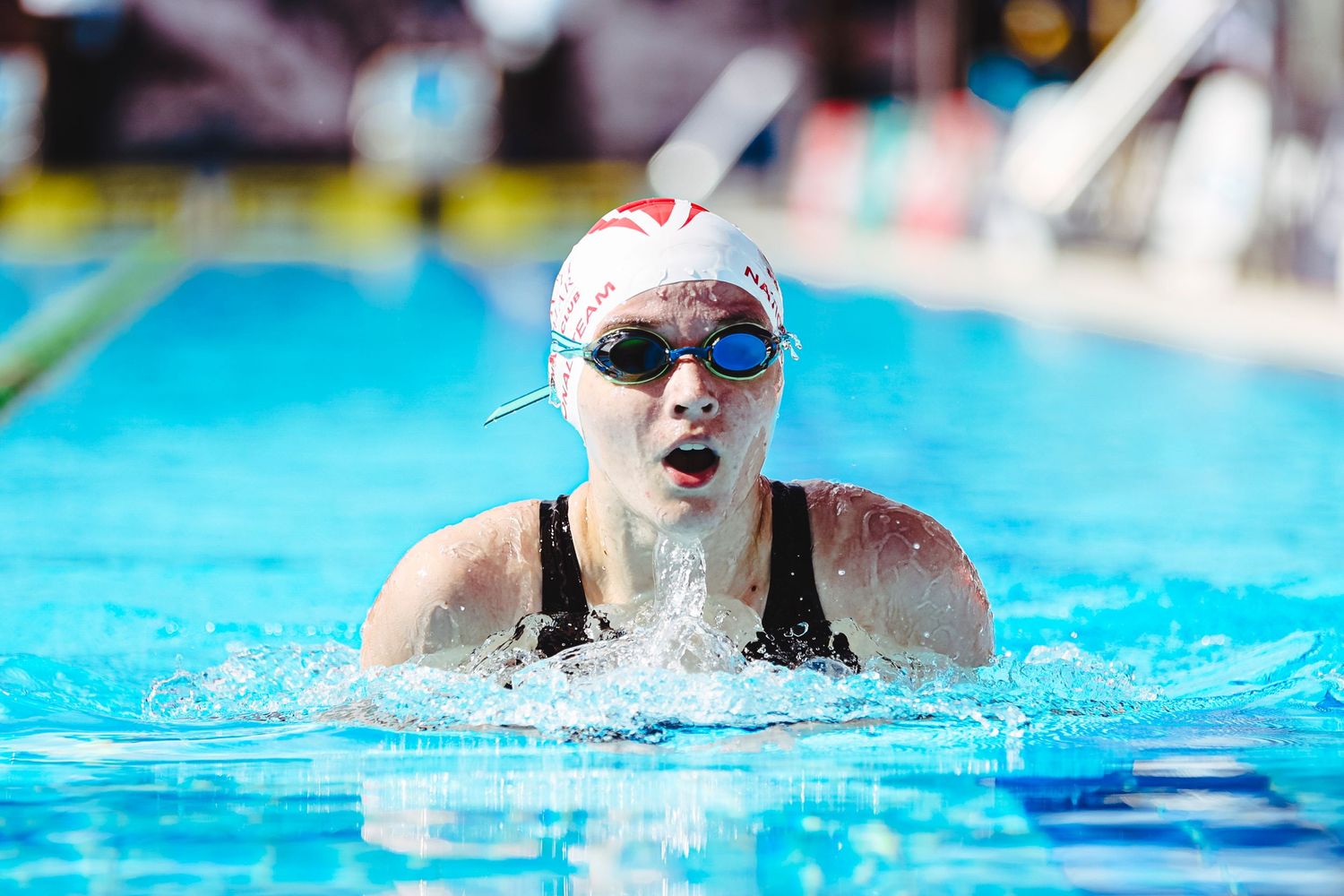 Young swimmer proudly wearing a medal stands on podium at Gold Coast AIS swimming championship competition.