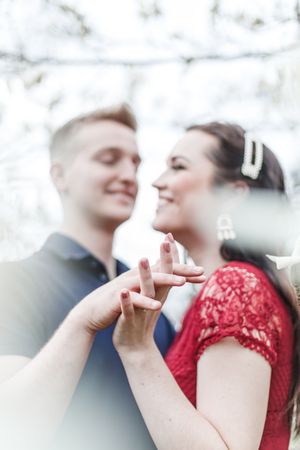A couple sharing an intimate moment outdoors with one wearing a red lace dress.