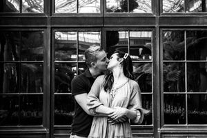 A romantic black and white photograph of a couple embracing in front of a window-paned storefront.