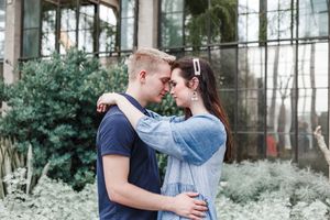 Romantic couple embraces in a serene forest setting during their engagement photo session.