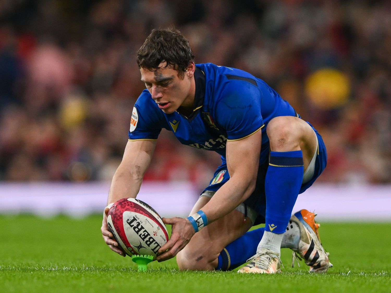 Rugby player in blue jersey dives to ground with ball during intense match action.