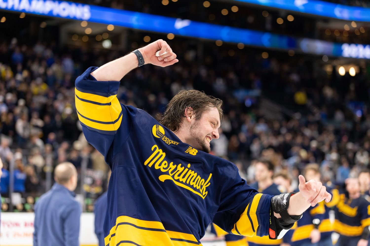 Hockey players celebrate victory on ice wearing navy and gold jerseys.
