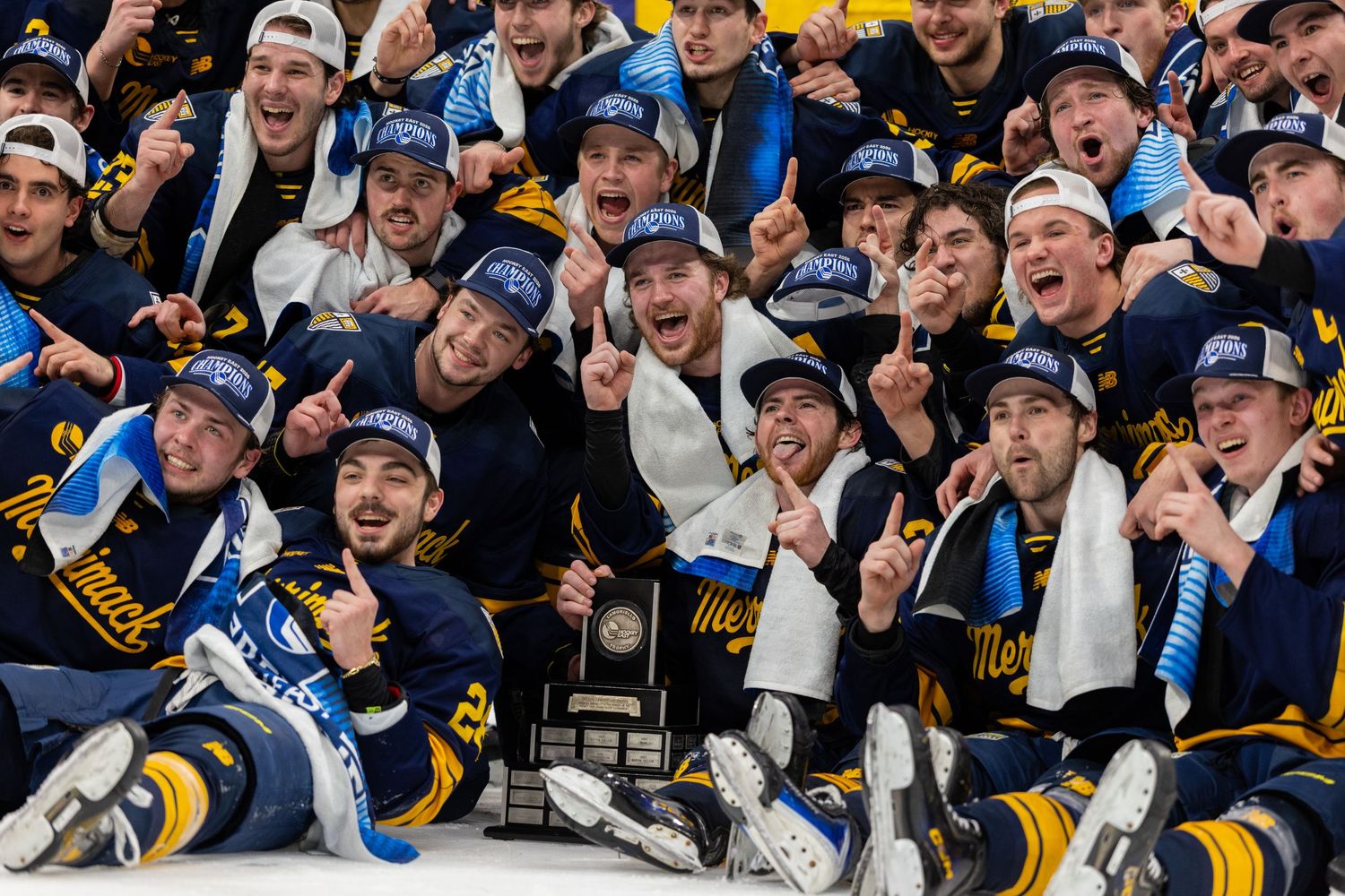 Large group of hockey players celebrate together wearing navy and gold uniforms.