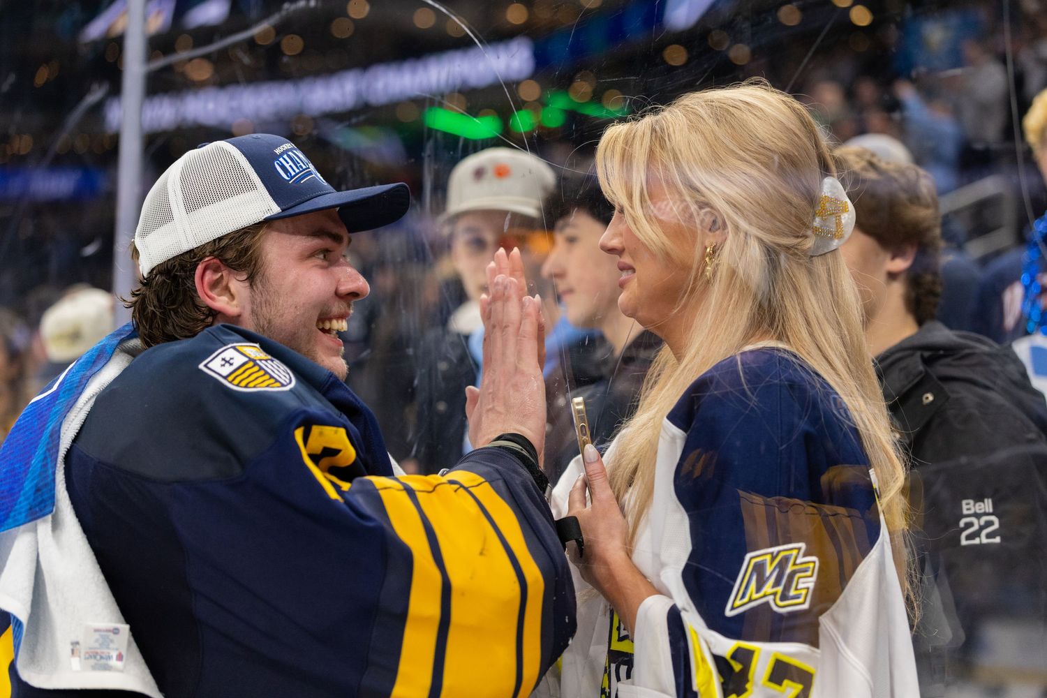 Hockey players and fans celebrate together at ice rink during championship event.