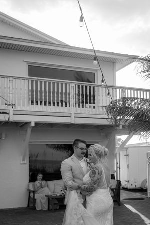 A black and white photo series showing a couple dancing together on a white balcony or porch of a house.