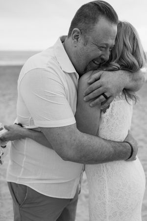A tender embrace between a couple in beach wedding attire captured in a series of black and white photos.