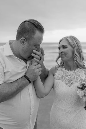 A romantic black and white photo sequence shows a couple sharing tender moments on their wedding day at the beach.