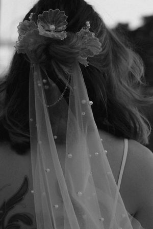 A delicate white bridal veil with floral details and pearls captured in black and white.