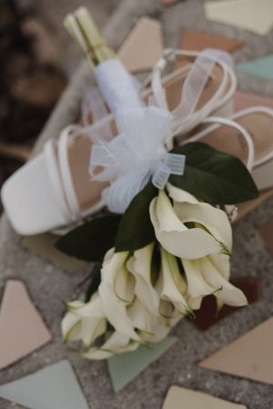 White calla lily boutonnieres with delicate ribbons arranged on a stone surface for an elegant wedding.
