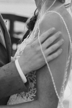 A black and white close-up photo of hands gently holding a pregnant belly, showing a tender maternal moment.