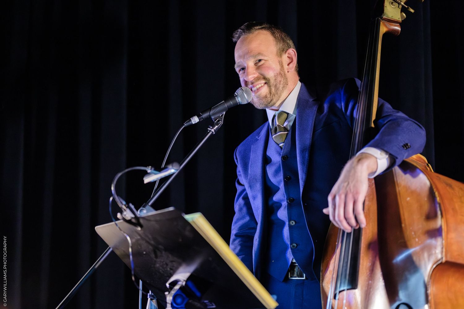 Chef leaning against bright orange and yellow storefront window.