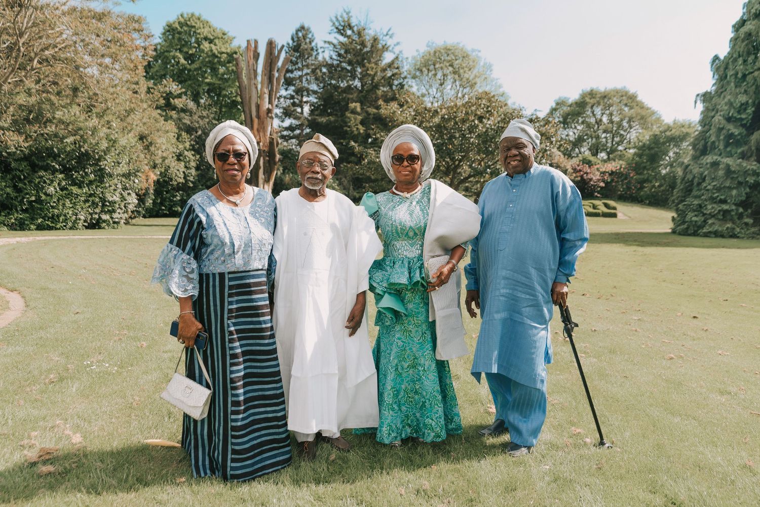A group of people in coordinated blue and white outfits pose together on a sunny grassy field.