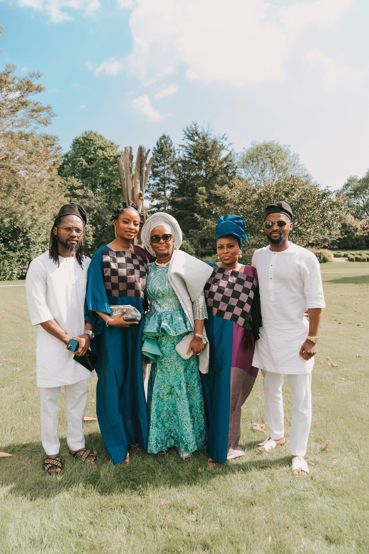 Family members in white, teal, and purple outfits gather for an outdoor photo on Orsett hall green grass.