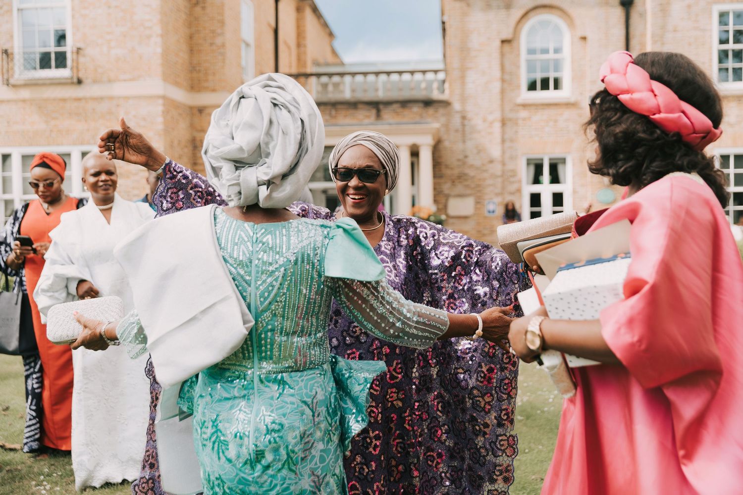 A group of people in traditional African attire dance and celebrate together at an outdoor gathering.