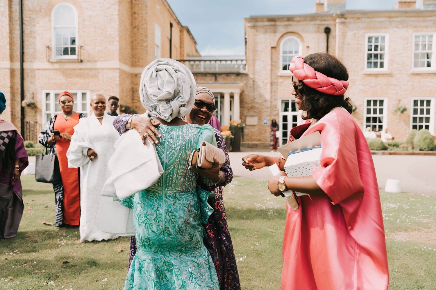 People in formal attire gather outside a grand brick building for a celebratory event.