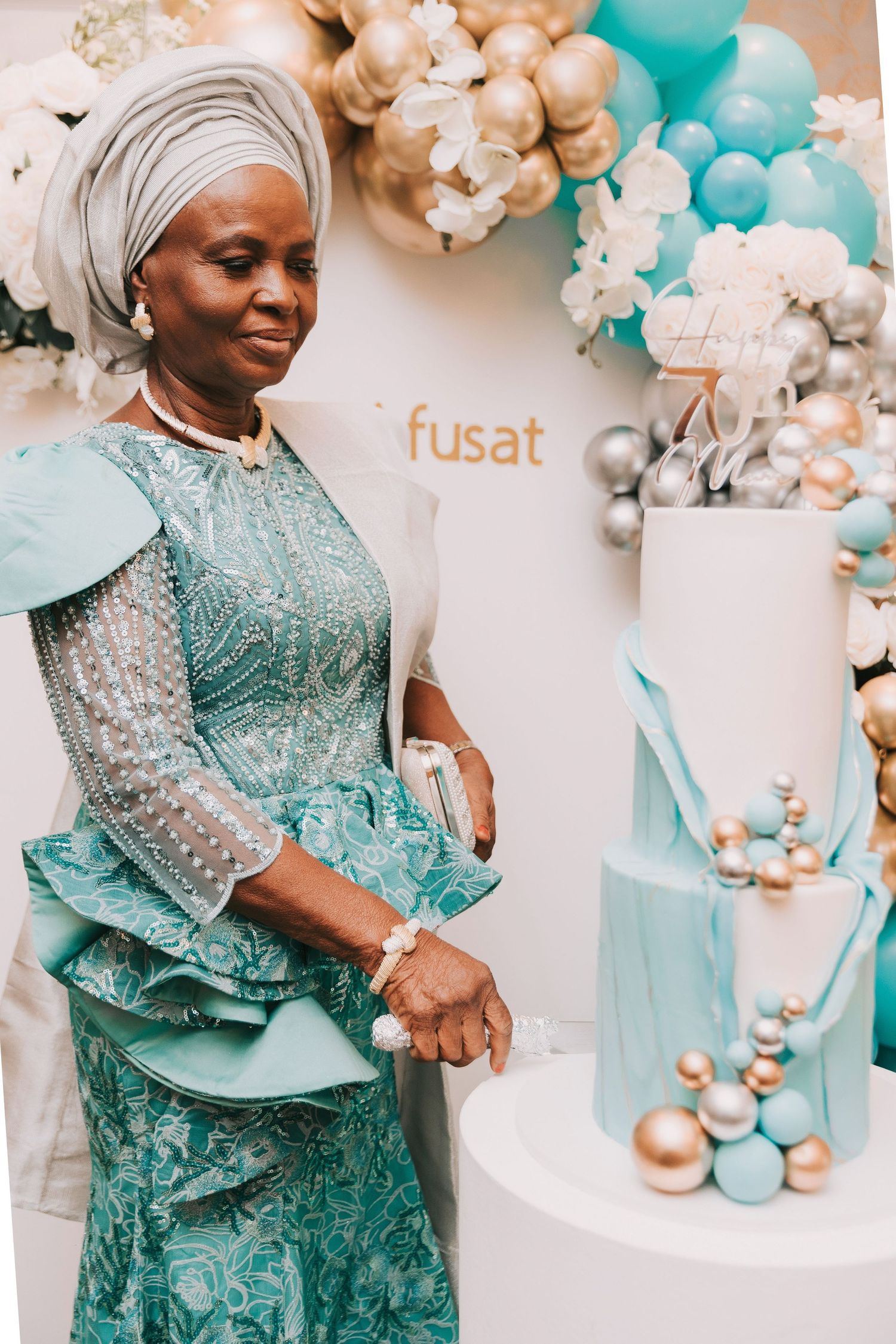 Festive celebration setup with teal and gold balloon decorations against a white backdrop.