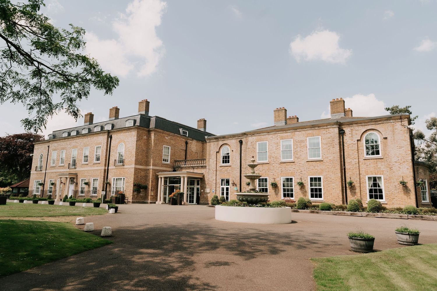 Exterior view of an elegant brick Georgian-style Orsett Hall venue building with manicured grounds.