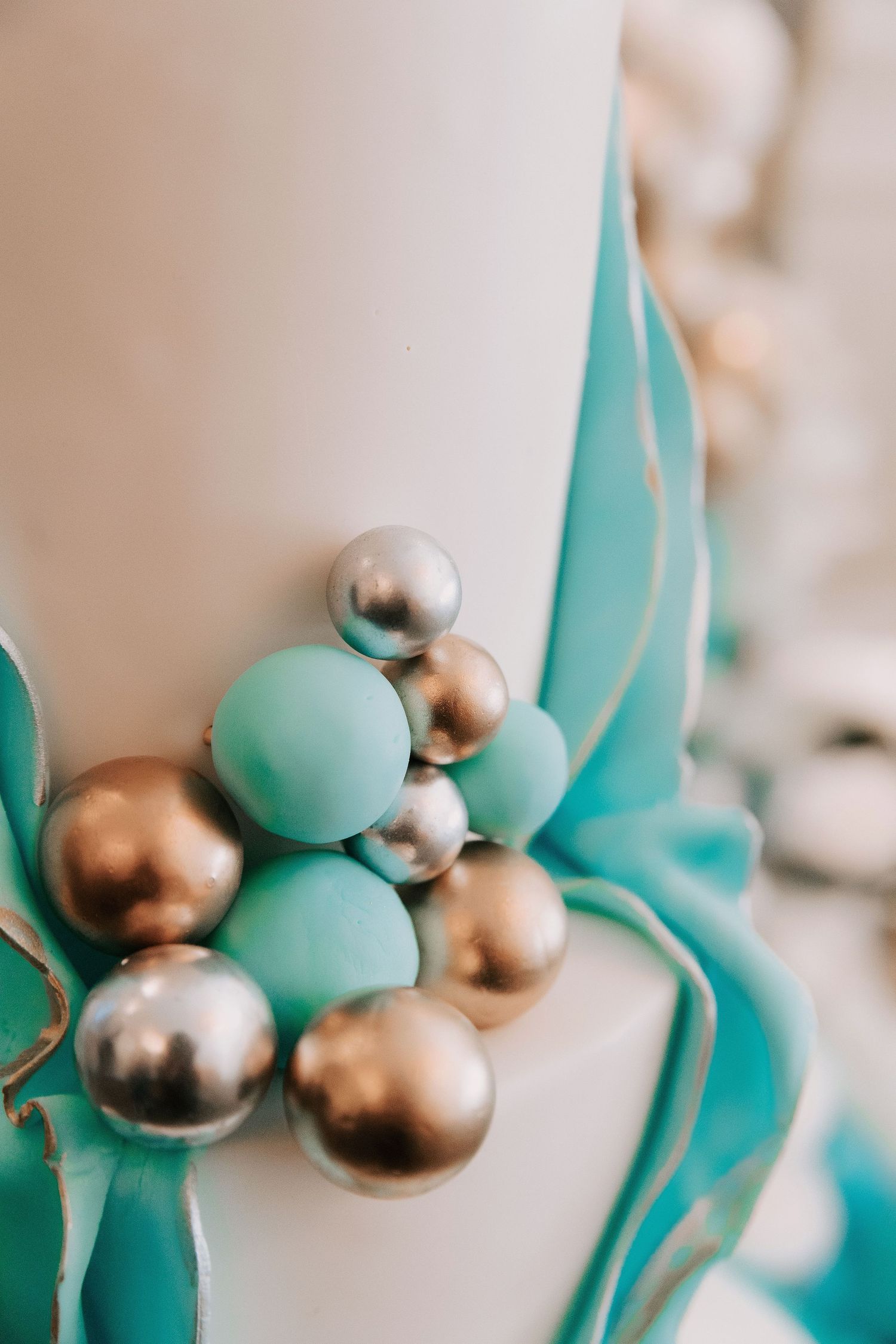 Decorative cake detail featuring mint green and metallic gold spherical ornaments in an elegant arrangement.