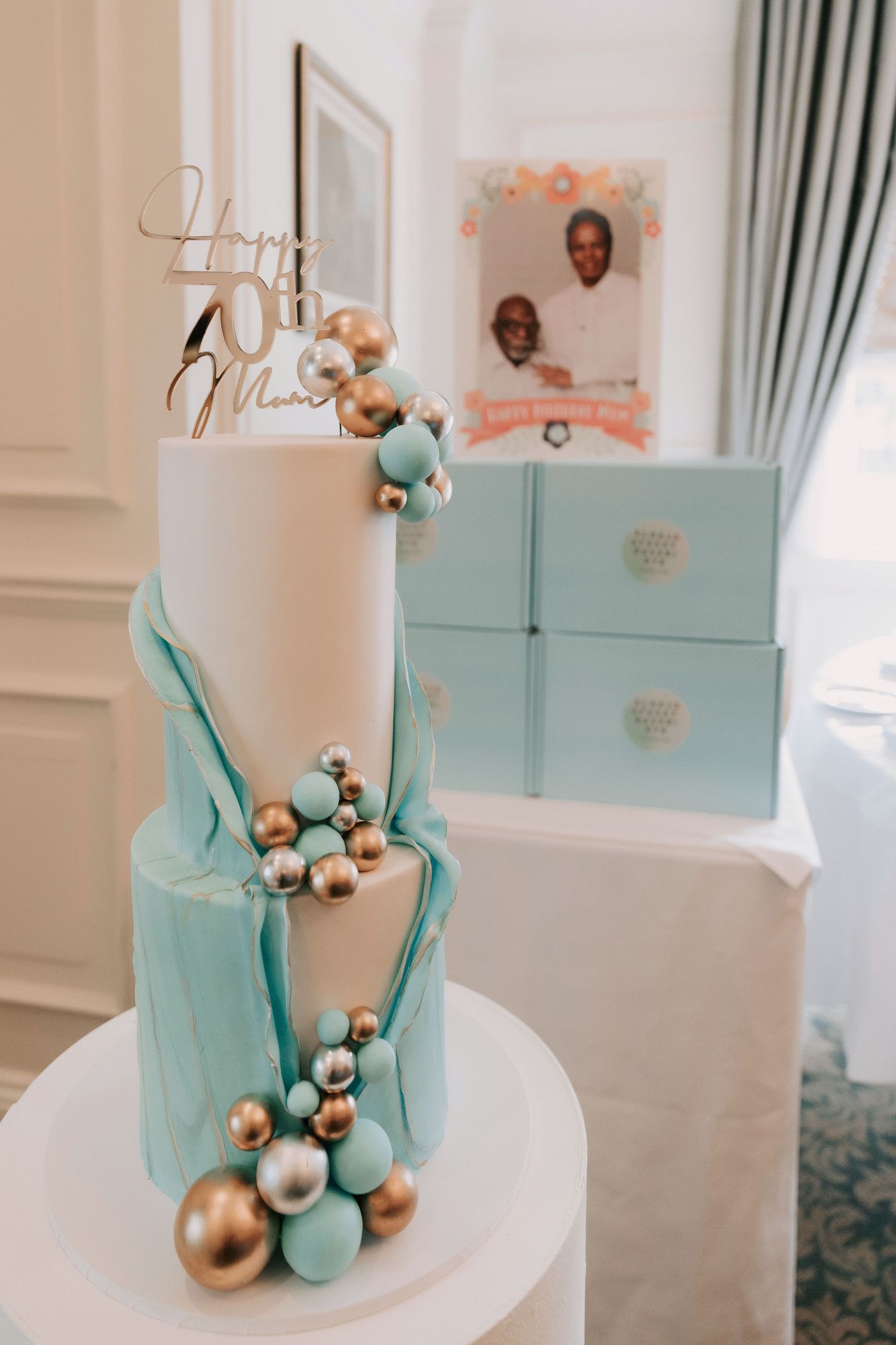 Elegant white wedding cake decorated with teal and gold geometric accents.