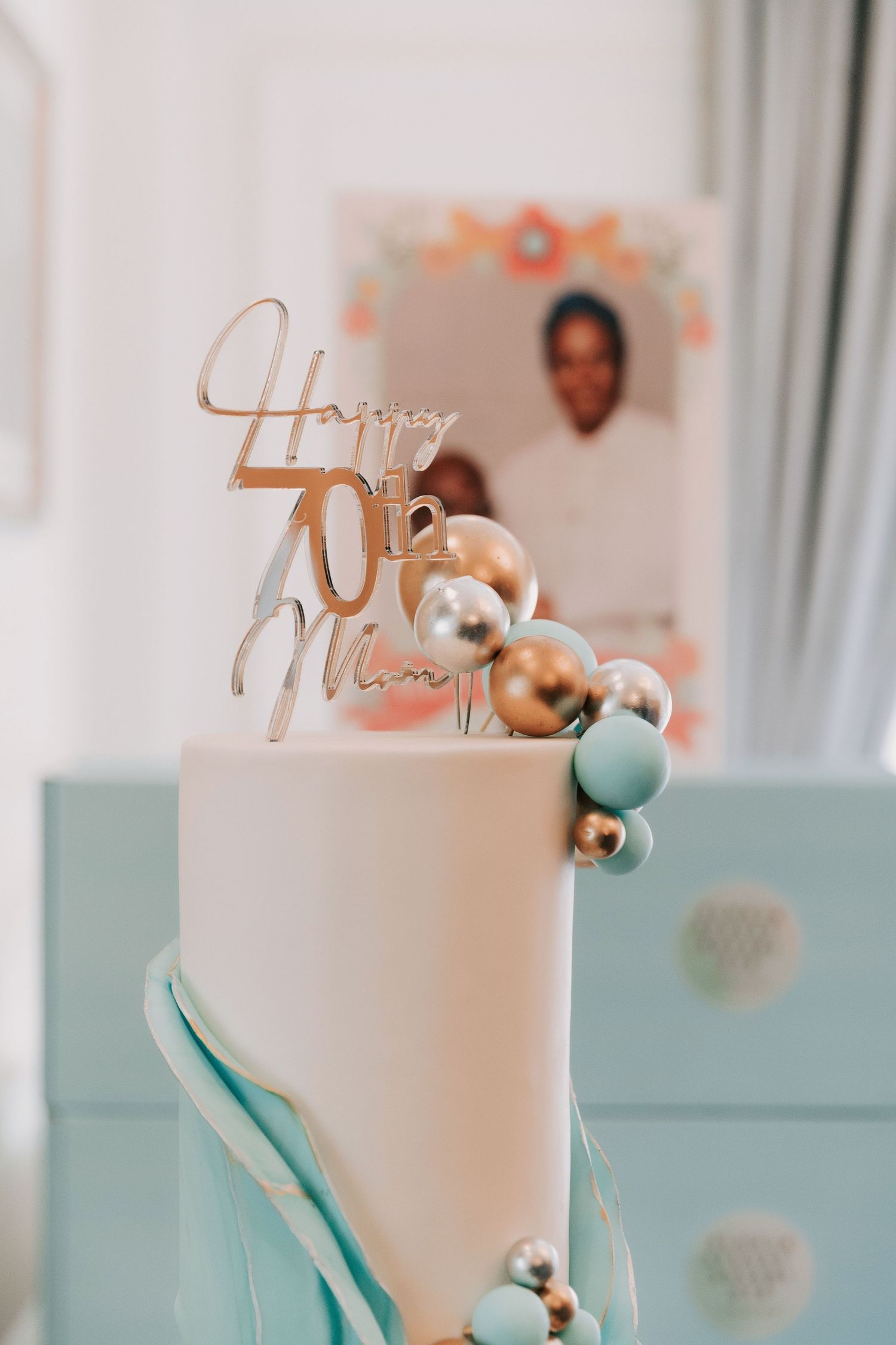Elegant white wedding cake decorated with teal and silver accents and metallic toppers.
