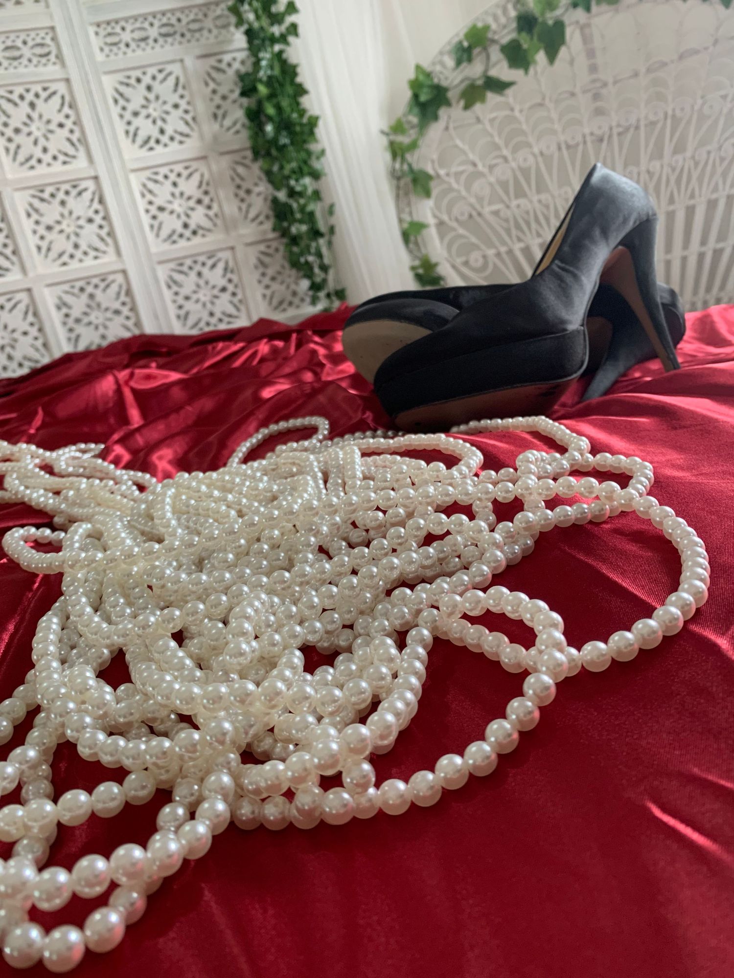 Pärlhalsband, högklackade skor, rött sidenlakan. Dessa finns att låna i Boudoir studion Photo By Jane i Höganäs.