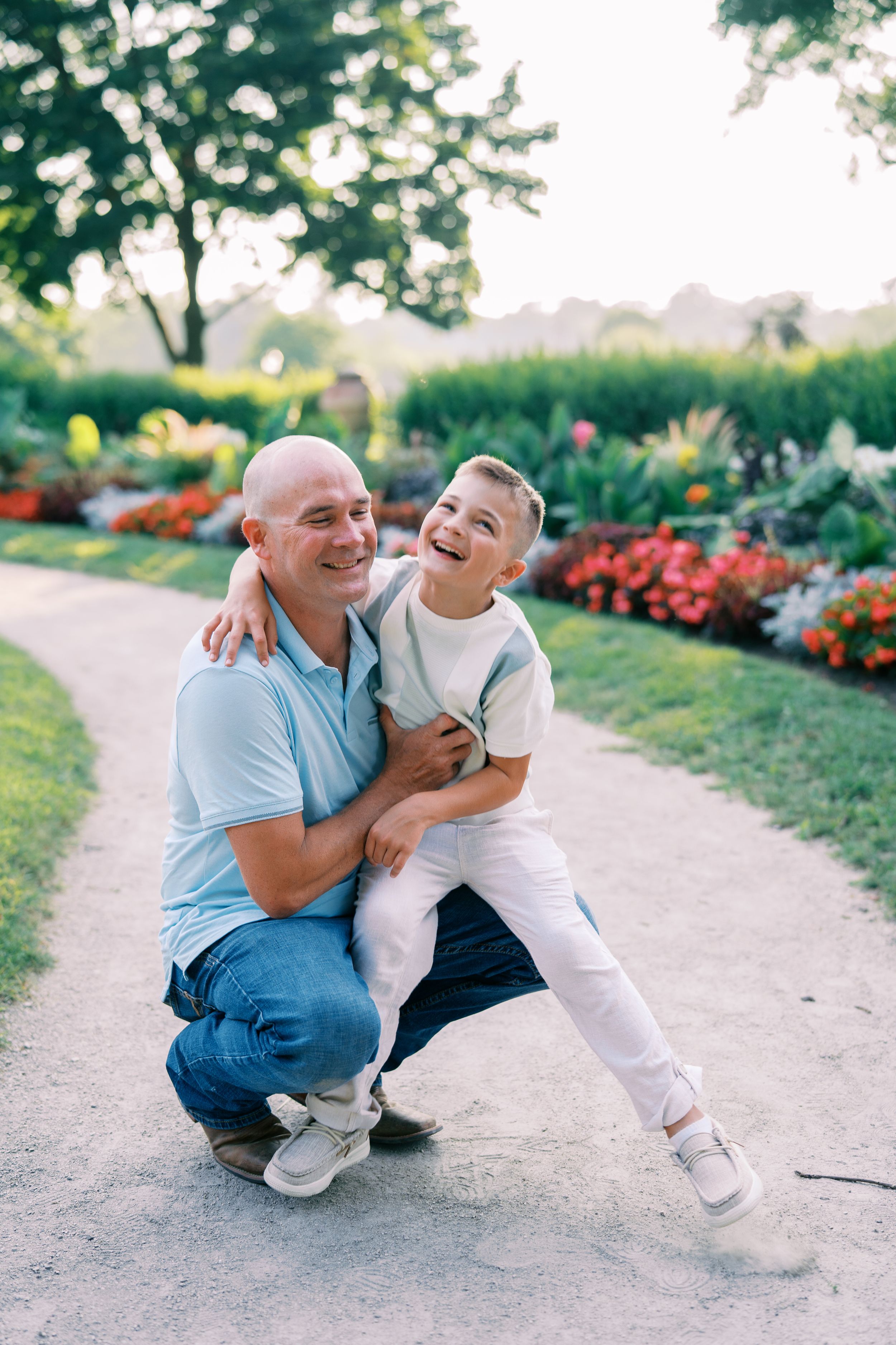 A heartwarming moment captured between two people laughing and embracing on a garden path.