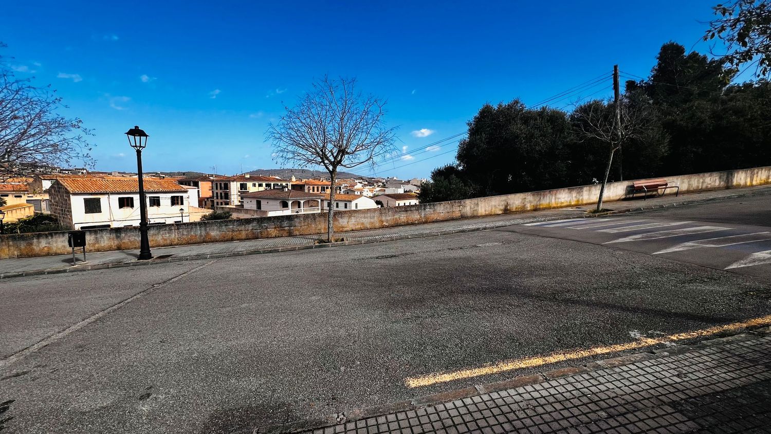 A paved parking lot with several cars parked, surrounded by trees and buildings.