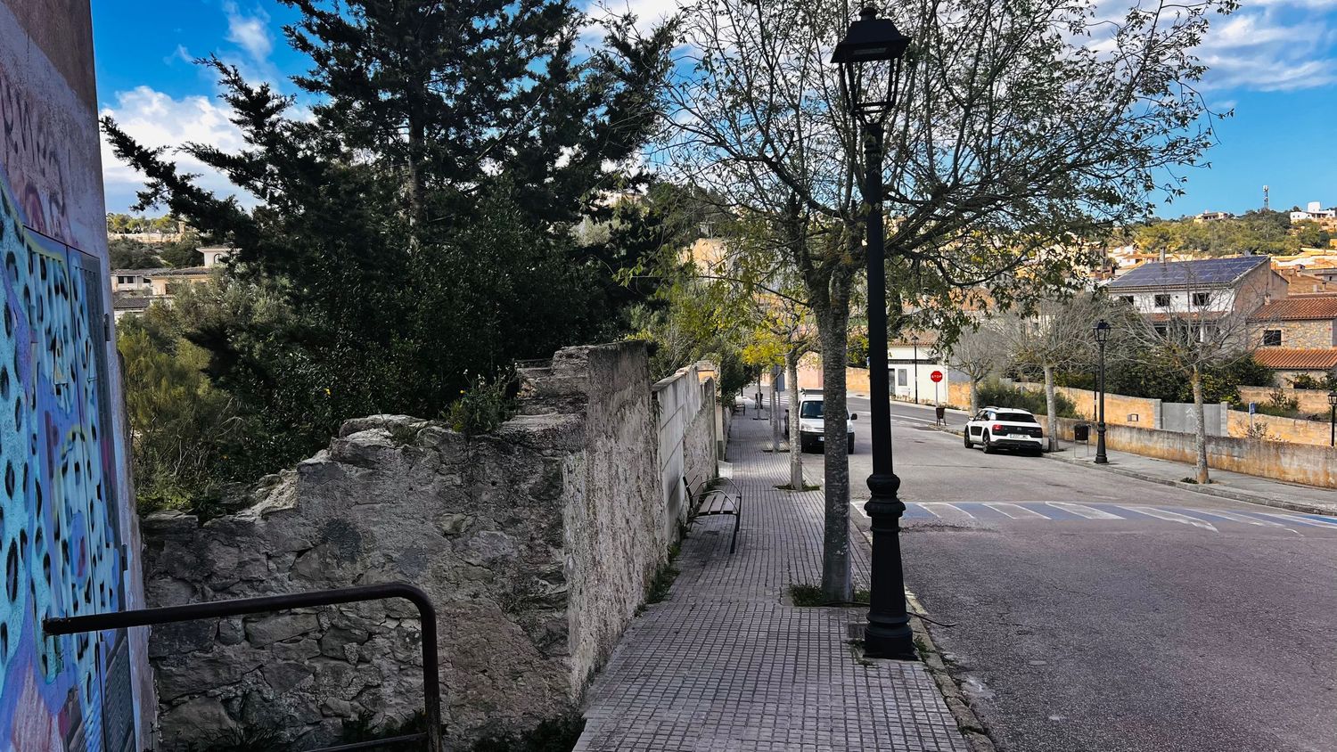 A paved sidewalk lined with trees and buildings in an urban setting.