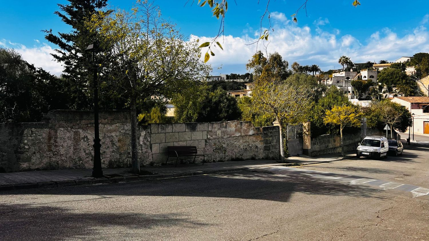 A scenic urban landscape with trees, buildings, and a paved street on a sunny day.