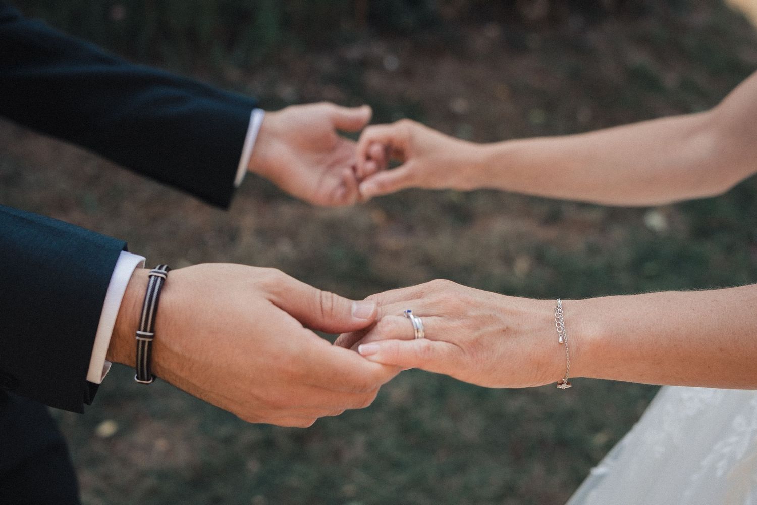 Close-up of hands exchanging rings during wedding ceremony.
