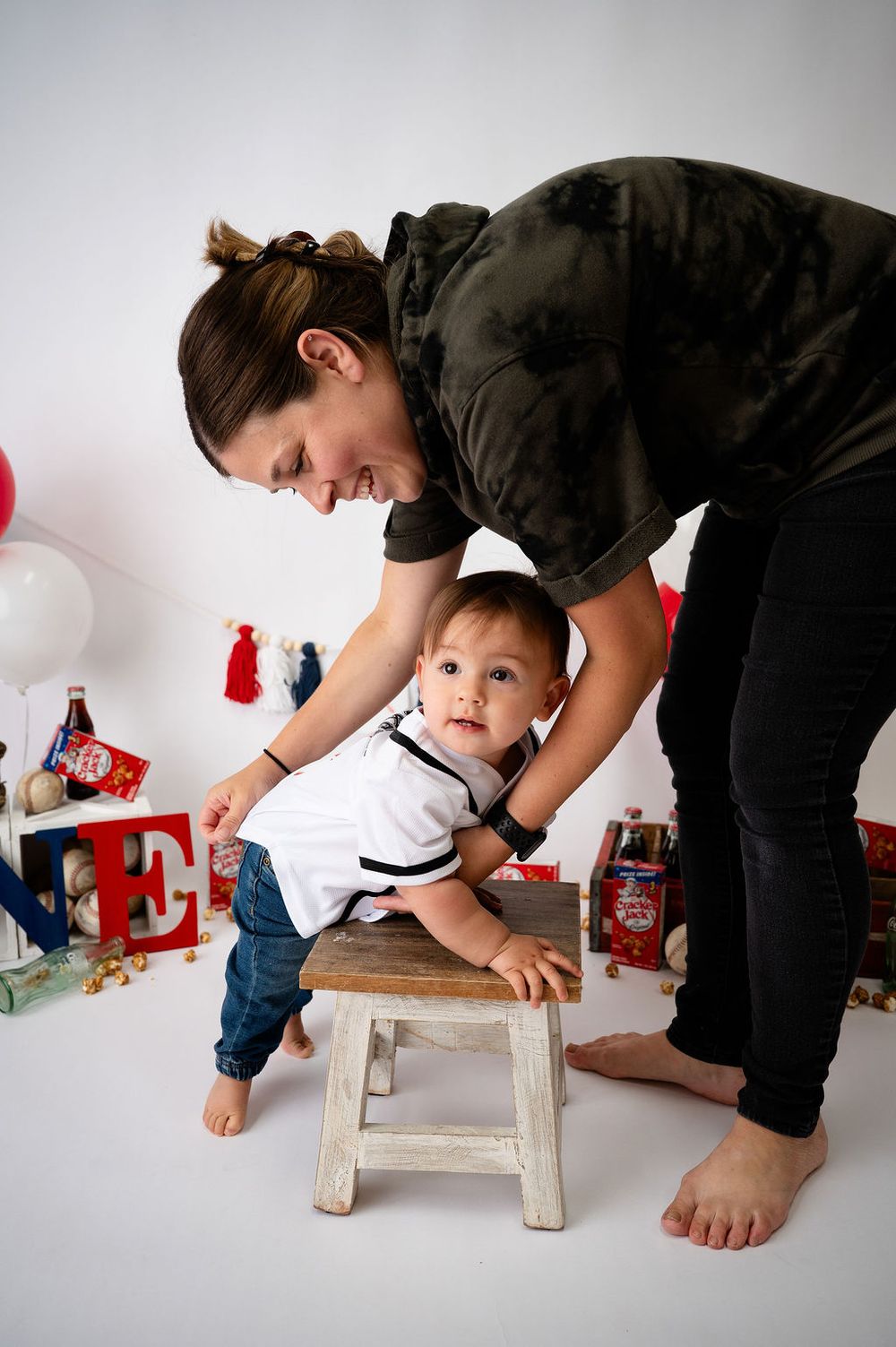 A series of photos showing a parent helping a small child balance on a wooden stool against a white background.