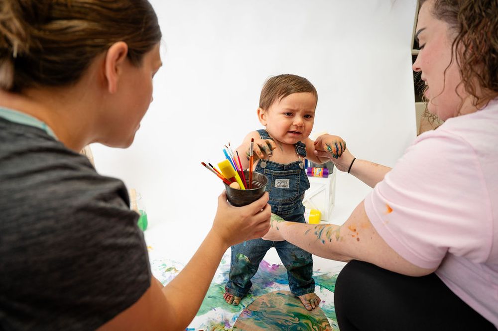 Children engage in colorful finger painting activities at a table with art supplies and paint.
