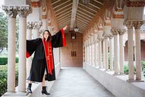 A long white USC colonnade walkway with ornate architectural details and red accents stretches into the distance.