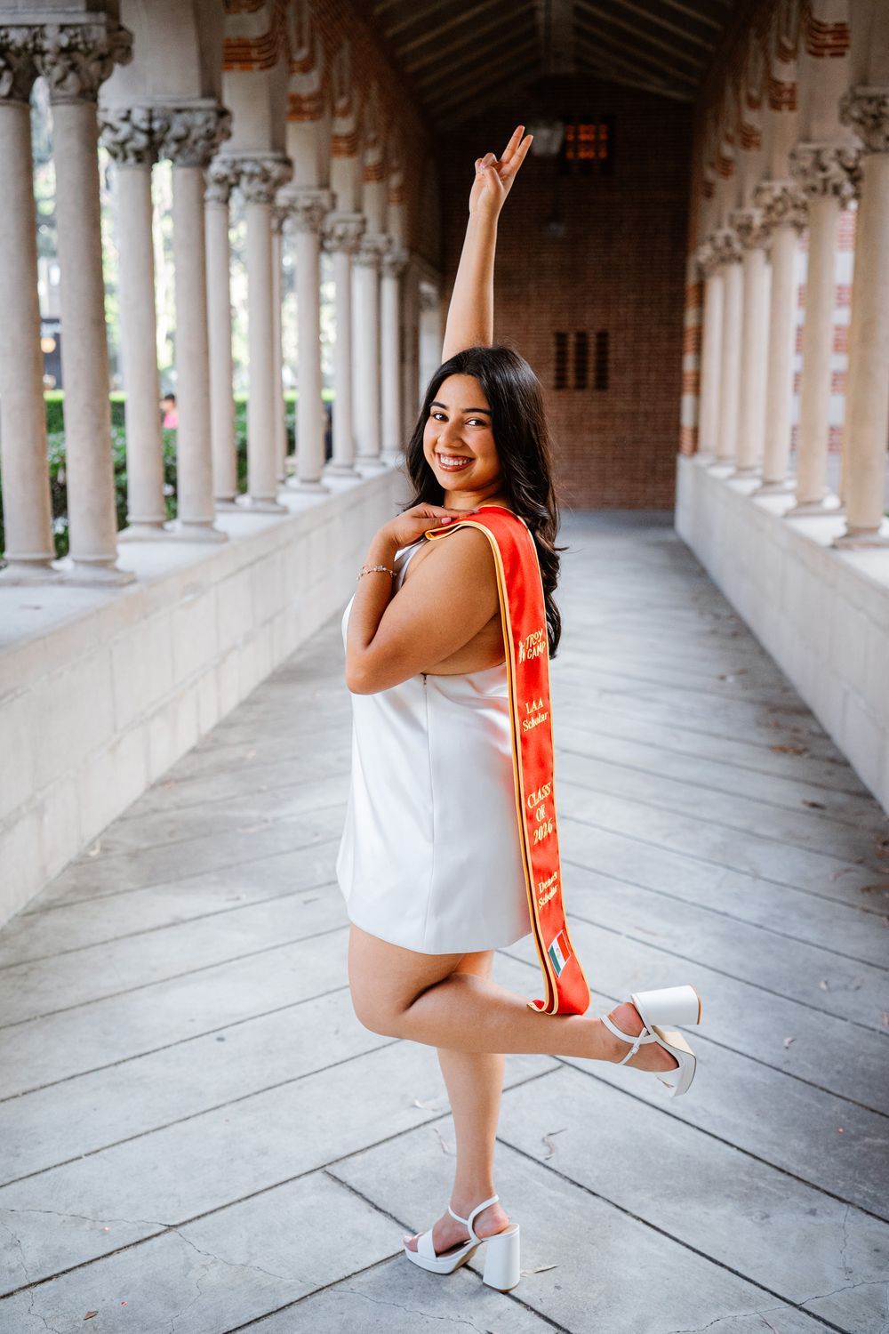 A series of photos showing a dancer in white performing graceful poses along a historic colonnade USC hallway.