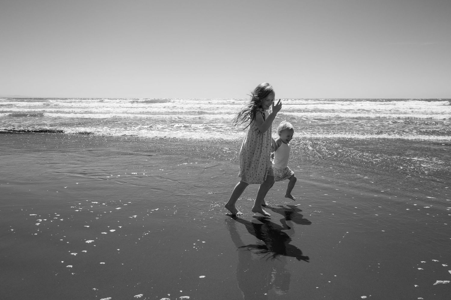 siblings running at the beach during family session in the morning