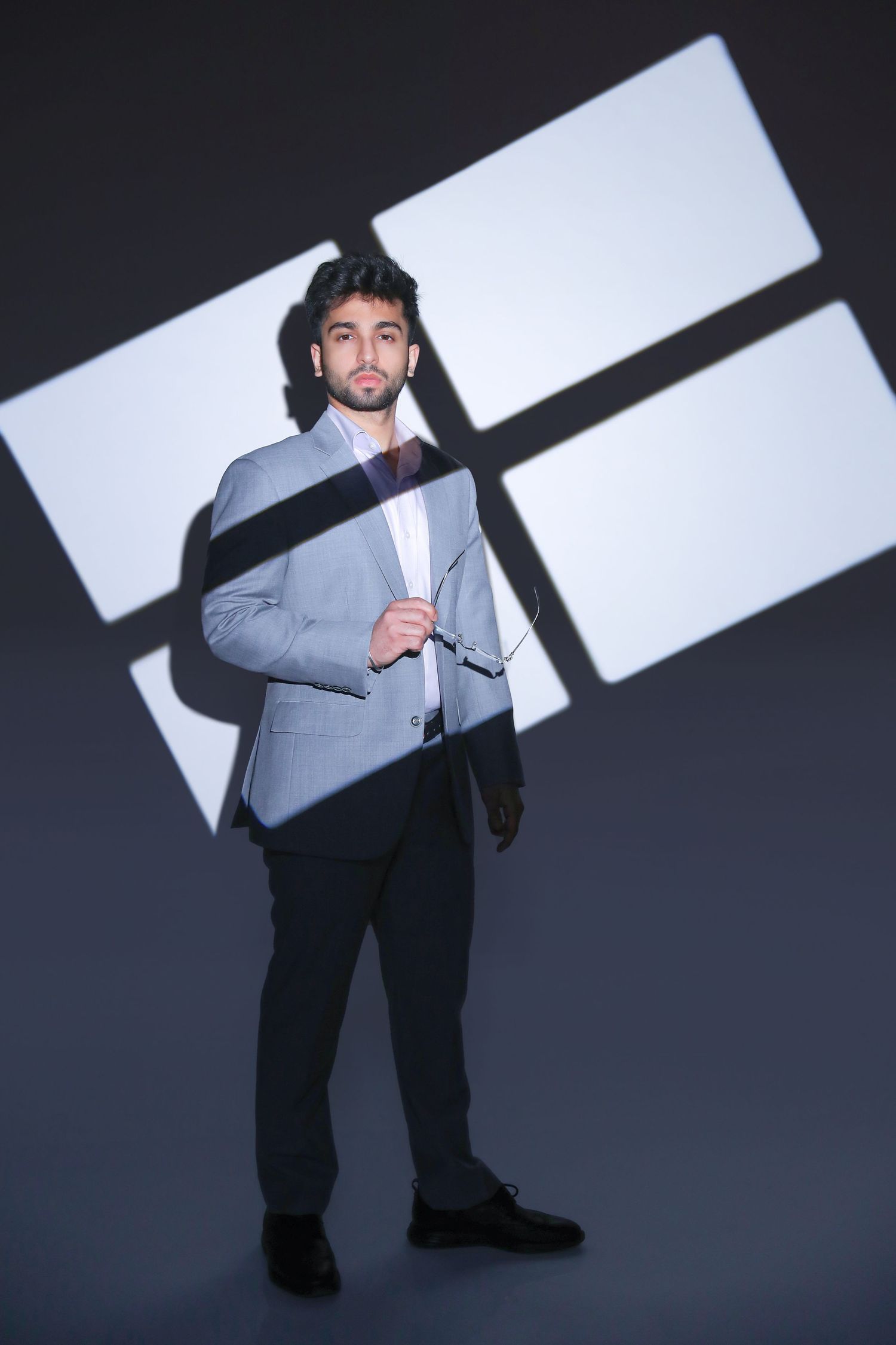A person in a gray suit poses dramatically against a stark black and white geometric background in a creative photo series.