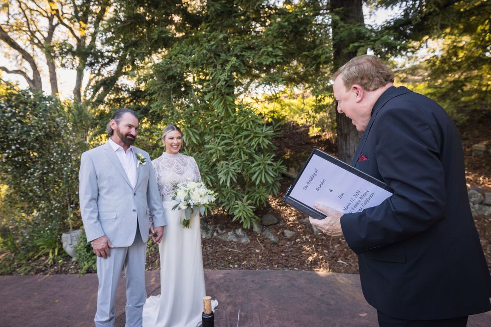 Wedding couple poses together outdoors in a garden setting with natural greenery and trees.