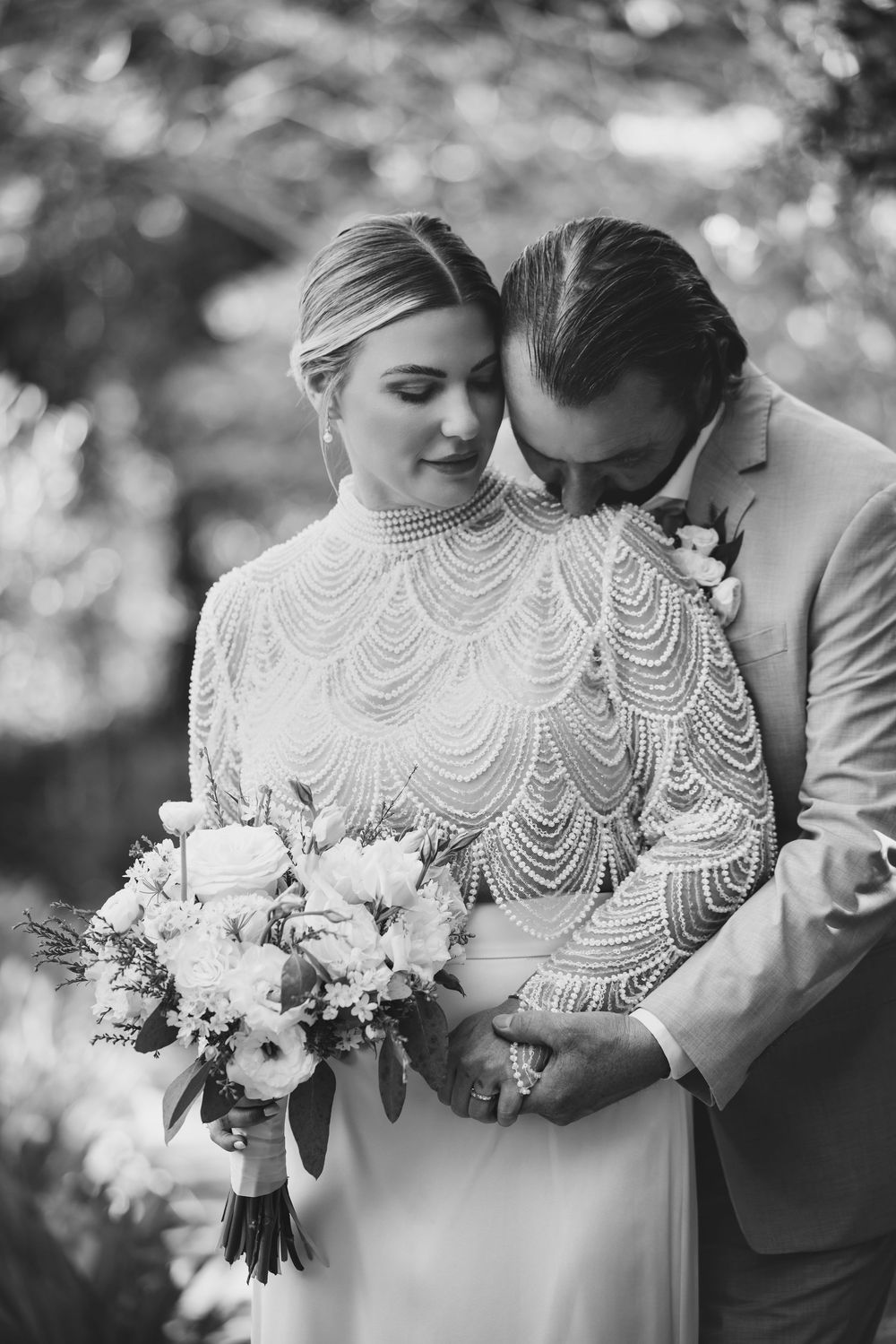 Black and white wedding photos showing elegant beaded back detail of bridal gown with white floral bouquet.