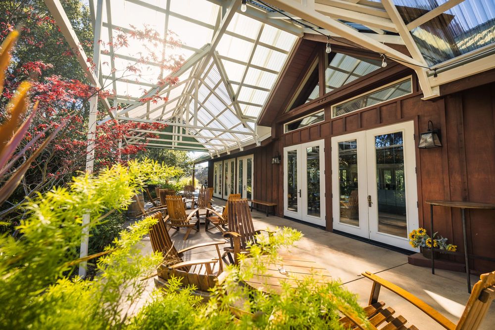 Bright greenhouse-style venue with glass ceiling and wooden beams creating an elegant indoor-outdoor atmosphere.
